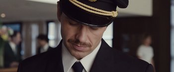 Movie still from “Colonia” (2015), directed by Florian Gallenberger – A person wearing a hat and a tie; Close Up shot, Low angle