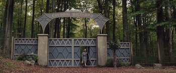 Movie still from “Colonia” (2015), directed by Florian Gallenberger – A woman walking through a gate in the woods; Extreme Wide shot, Low angle