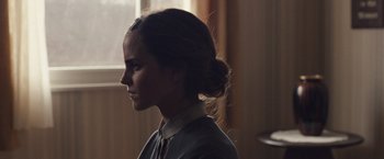 Movie still from “Colonia” (2015), directed by Florian Gallenberger – A woman with a bun is looking to the side; Close Up shot, Over the shoulder angle