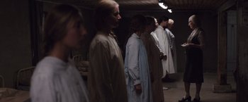 Movie still from “Colonia” (2015), directed by Florian Gallenberger – A group of people standing next to each other in a room; Wide shot, High angle