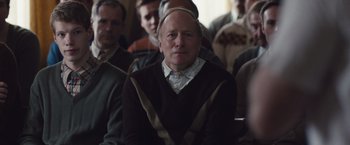 Movie still from “Colonia” (2015), directed by Florian Gallenberger – A group of people sitting in a room; Medium shot, Over the shoulder angle