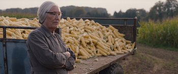 Movie still from “Colonia” (2015), directed by Florian Gallenberger – An older man standing in front of a truck filled with corn; Close Up shot, Over the shoulder angle