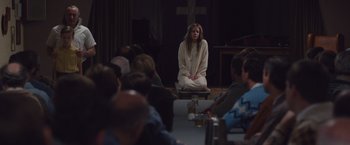 Movie still from “Colonia” (2015), directed by Florian Gallenberger – A woman sitting on the ground in front of a group of people; Wide shot, High angle