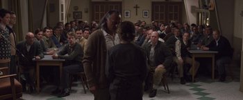 Movie still from “Colonia” (2015), directed by Florian Gallenberger – A man and a woman in front of a crowd of people; Medium shot, Over the shoulder angle