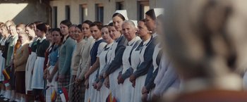 Movie still from “Colonia” (2015), directed by Florian Gallenberger – A group of women standing next to each other in front of a building; Medium shot, Over the shoulder angle