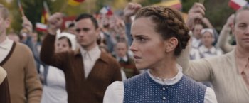 Movie still from “Colonia” (2015), directed by Florian Gallenberger – A woman in polka dot shirt standing in front of a crowd of people; Close Up shot, Over the shoulder angle