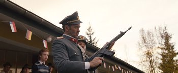 Movie still from “Colonia” (2015), directed by Florian Gallenberger – A man in a uniform holding a gun; Medium shot, Low angle