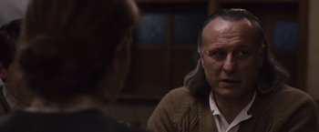 Movie still from “Colonia” (2015), directed by Florian Gallenberger – A man with long gray hair is talking to another man; Close Up shot, Over the shoulder angle