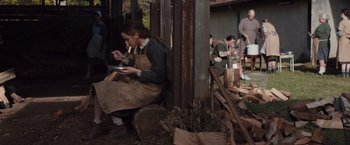 Movie still from “Colonia” (2015), directed by Florian Gallenberger – A woman sitting on a bench with a plate in her hand; Wide shot, High angle