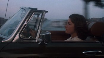 Movie still from “Coma” (1978), directed by Michael Crichton – A woman sitting in the driver's seat of a car looking out the window; Medium shot, Over the shoulder angle