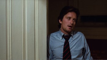 Movie still from “Coma” (1978), directed by Michael Crichton – A man wearing a shirt and tie sitting in front of a wall; Medium shot, Over the shoulder angle
