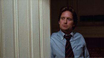 Movie still from “Coma” (1978), directed by Michael Crichton – A man wearing a shirt and a tie looking out a window; Medium shot, Low angle