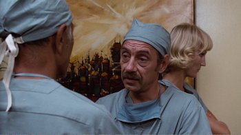 Movie still from “Coma” (1978), directed by Michael Crichton – A man wearing a surgical mask and a blue hat; Medium shot, Low angle