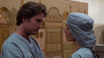 Movie still from “Coma” (1978), directed by Michael Crichton – A man and a woman in scrubs looking at one another; Close Up shot, Low angle