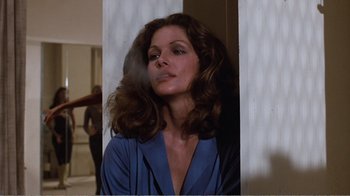 Movie still from “Coma” (1978), directed by Michael Crichton – A woman in a blue shirt is standing in front of a mirror; Medium shot, Low angle
