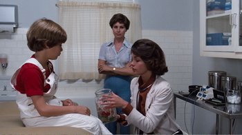 Movie still from “Coma” (1978), directed by Michael Crichton – Three women in a room one is holding a jar of strawberries; Medium shot, Over the shoulder angle