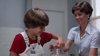 Movie still from “Coma” (1978), directed by Michael Crichton – A boy and a woman are smiling at each other; Medium shot, Low angle