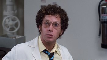 Movie still from “Coma” (1978), directed by Michael Crichton – A man with curly hair wearing glasses and a white jacket; Close Up shot, Low angle