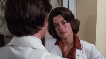 Movie still from “Coma” (1978), directed by Michael Crichton – A woman in a white lab coat looking in the mirror; Close Up shot, Over the shoulder angle