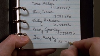 Movie still from “Coma” (1978), directed by Michael Crichton – A hand holding a pen over a notebook with names written on it; Extreme Close Up shot, High angle