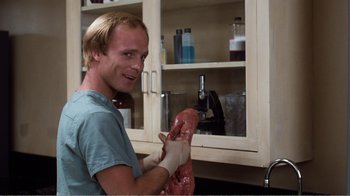 Movie still from “Coma” (1978), directed by Michael Crichton – A man in a blue t - shirt and white gloves is holding a piece of meat; Medium shot, Low angle