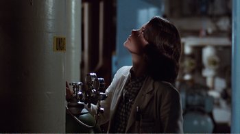 Movie still from “Coma” (1978), directed by Michael Crichton – A woman looking up into the sky while standing next to a pipe; Medium shot, Over the shoulder angle