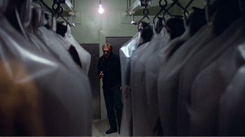 Movie still from “Coma” (1978), directed by Michael Crichton – A man standing next to a bunch of white suits; Medium shot, Low angle