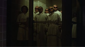 Movie still from “Coma” (1978), directed by Michael Crichton – A group of men in white robes standing next to each other in a bathroom; Wide shot, High angle