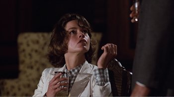 Movie still from “Coma” (1978), directed by Michael Crichton – A woman sitting in a chair holding a glass; Close Up shot, Over the shoulder angle