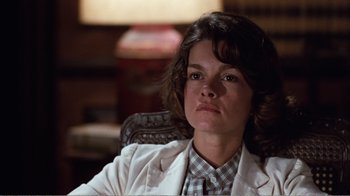 Movie still from “Coma” (1978), directed by Michael Crichton – A person sitting in a chair wearing a jacket; Close Up shot, Low angle