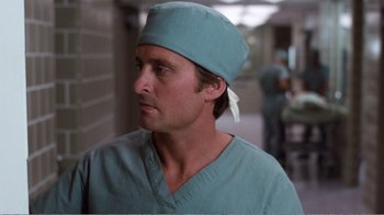 Movie still from “Coma” (1978), directed by Michael Crichton – A man wearing a surgical cap and a green shirt; Close Up shot, Low angle