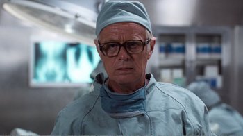 Movie still from “Coma” (1978), directed by Michael Crichton – A man wearing a surgical gown and a hat; Close Up shot, Low angle