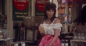 Movie still from “Come Back to the 5 & Dime Jimmy Dean, Jimmy Dean” (1982), directed by Robert Altman – A woman holding a glass of beer while sitting on a counter; Medium shot, Over the shoulder angle