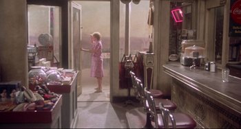 Movie still from “Come Back to the 5 & Dime Jimmy Dean, Jimmy Dean” (1982), directed by Robert Altman – A woman standing in the doorway of a diner; Wide shot, High angle
