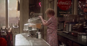 Movie still from “Come Back to the 5 & Dime Jimmy Dean, Jimmy Dean” (1982), directed by Robert Altman – An older woman in a floral dress at a soda fountain; Wide shot, High angle