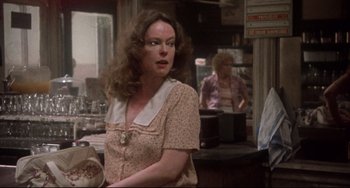 Movie still from “Come Back to the 5 & Dime Jimmy Dean, Jimmy Dean” (1982), directed by Robert Altman – A woman in a pink dress is in a kitchen; Medium shot, Over the shoulder angle
