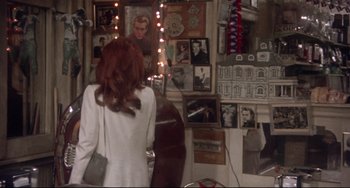 Movie still from “Come Back to the 5 & Dime Jimmy Dean, Jimmy Dean” (1982), directed by Robert Altman – A woman standing in front of a wall with pictures on it; Medium shot, Over the shoulder angle