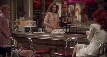 Movie still from “Come Back to the 5 & Dime Jimmy Dean, Jimmy Dean” (1982), directed by Robert Altman – A woman standing at a counter in front of a mirror; Medium shot, Over the shoulder angle