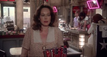 Movie still from “Come Back to the 5 & Dime Jimmy Dean, Jimmy Dean” (1982), directed by Robert Altman – A woman in a dress holding a bunch of boxes; Medium shot, Over the shoulder angle