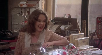 Movie still from “Come Back to the 5 & Dime Jimmy Dean, Jimmy Dean” (1982), directed by Robert Altman – A woman sitting at a table in front of a stack of cds; Medium shot, Over the shoulder angle