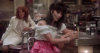 Movie still from “Come Back to the 5 & Dime Jimmy Dean, Jimmy Dean” (1982), directed by Robert Altman – A woman sitting at a table with a bottle of beer in front of her; Medium shot, Over the shoulder angle