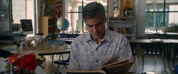 Movie still from “The Descendants” (2011), directed by Alexander Payne – A man sitting at a table looking at a book; Medium shot, Over the shoulder angle