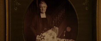 Movie still from “The Descendants” (2011), directed by Alexander Payne – An older woman holding an american flag in front of a staircase; Close Up shot, Low angle