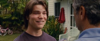 Movie still from “The Descendants” (2011), directed by Alexander Payne – A young man smiling for the camera in front of a house; Close Up shot, Over the shoulder angle