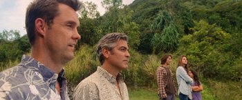 Movie still from “The Descendants” (2011), directed by Alexander Payne – Three men are standing in a grassy area; Medium shot, Over the shoulder angle
