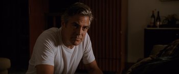 Movie still from “The Descendants” (2011), directed by Alexander Payne – A man in a white t - shirt is looking at the camera; Close Up shot, Low angle