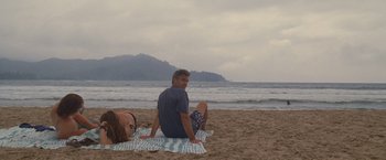 Movie still from “The Descendants” (2011), directed by Alexander Payne – A man and a woman sitting on a towel on the beach; Wide shot, Over the shoulder angle
