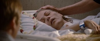 Movie still from “The Descendants” (2011), directed by Alexander Payne – An older woman laying in a casket with a hand touching her head; Close Up shot, High angle