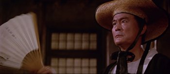 An older man wearing a straw hat in a room