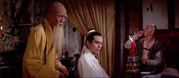 A man sitting in front of another man in front of a curtain